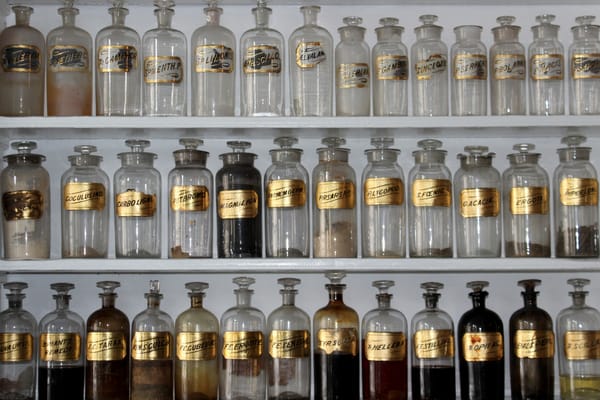 Photo of antique glass medicine or herb bottles with gold labels and stopper tops.