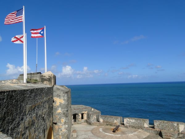 Photo of flags waving against a blue sky at Castillo San Felipe del Morro in San Juan, Puerto Rico.